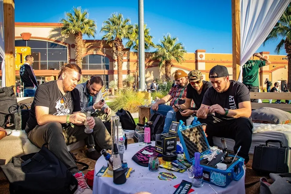 People gathered outdoors around a table with drinks and snacks in a sunny courtyard.