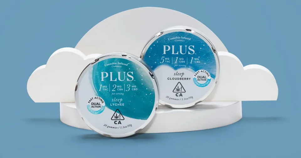 Two blue PLUS branded round containers on a white cloud-shaped stand against a blue background