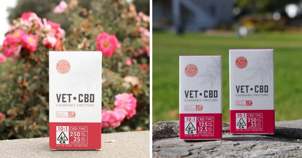 Two VET CBD product boxes in pink and white, displayed outdoors with flowers in the background.