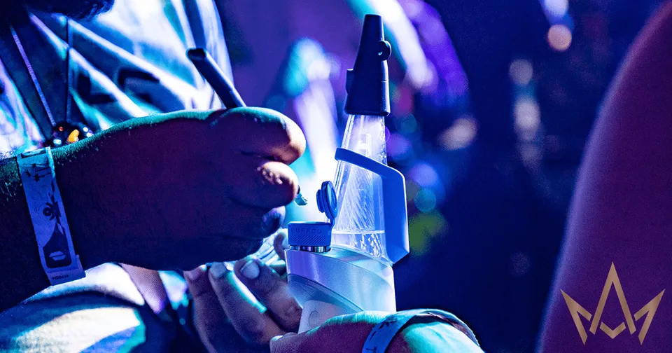 Hands adjusting a clear bottle on a stage lit in blue and purple