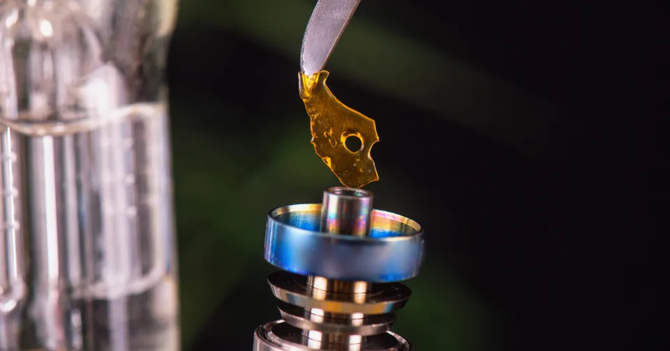 Gold liquid dripping from a pipette into a blue-rimmed lab vial