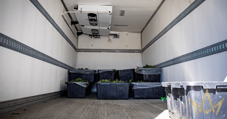 Interior of a moving truck with several blue bins and boxes stacked along the back wall.