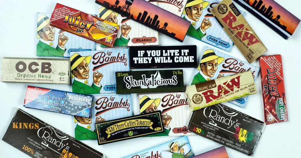 Assorted colorful rolling paper packs scattered on a white background.