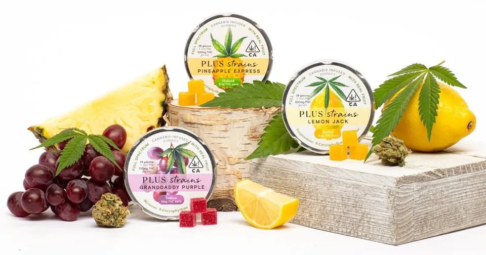 Cannabis-infused product jars and gummies displayed with grapes, lemon, and pineapple slices