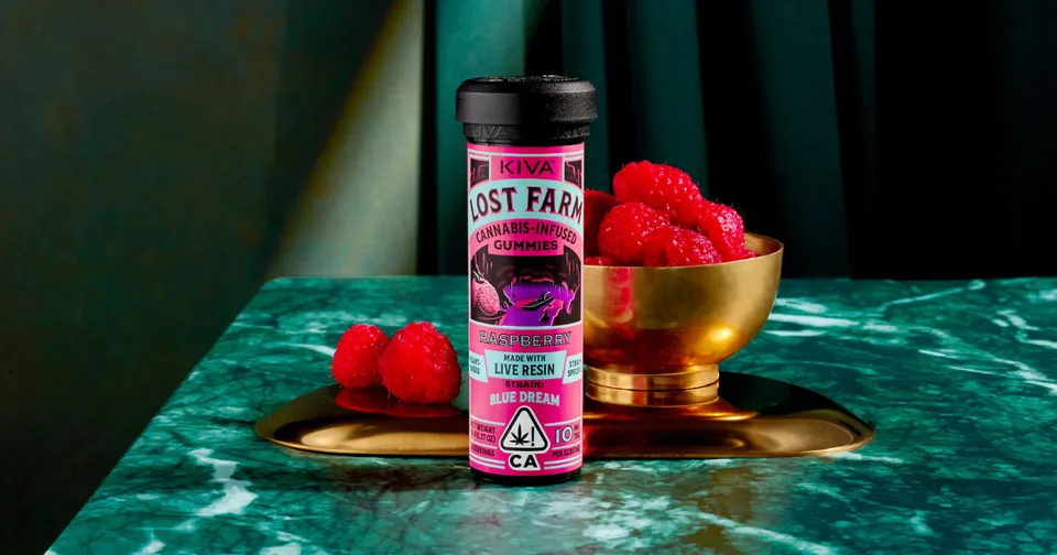 Pink bottle labeled “Lost Farm” with raspberries beside a gold bowl on a marble surface.