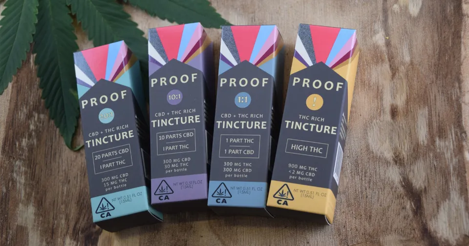 Four colorful Proof Tincture boxes lined up on a wooden surface.
