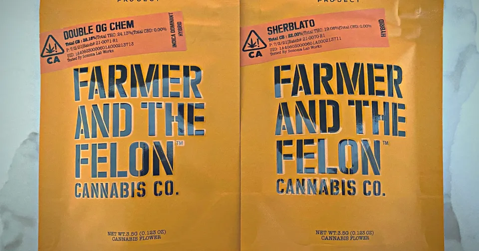 Two orange cannabis bags labeled “Farmer and the Felon” on a flat surface
