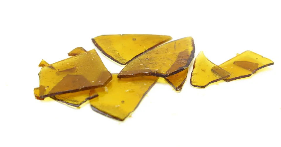 Broken yellow glass shards scattered on a white background