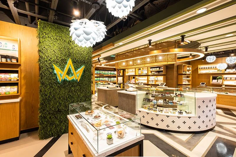 View across the Mission Valley store from the edibles room, with a green logo wall and illuminated circular flower bar.