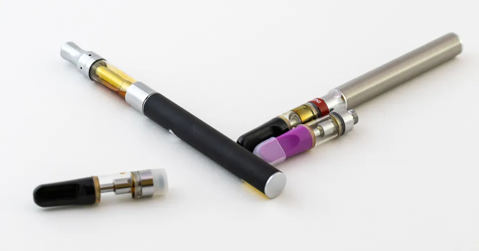 Two vape pens with black, silver, gold, and purple accents on a white background