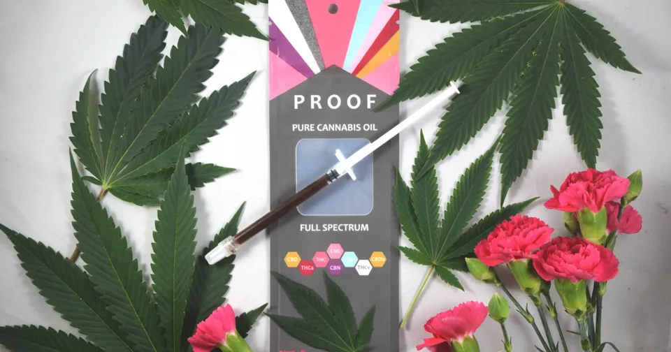 Cannabis leaves and pink flowers around a PROOF vape cartridge package on a gray background