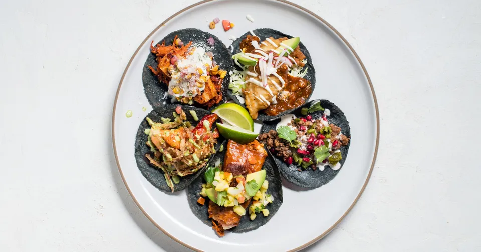 Six stuffed mushrooms topped with herbs and cheese on a white plate