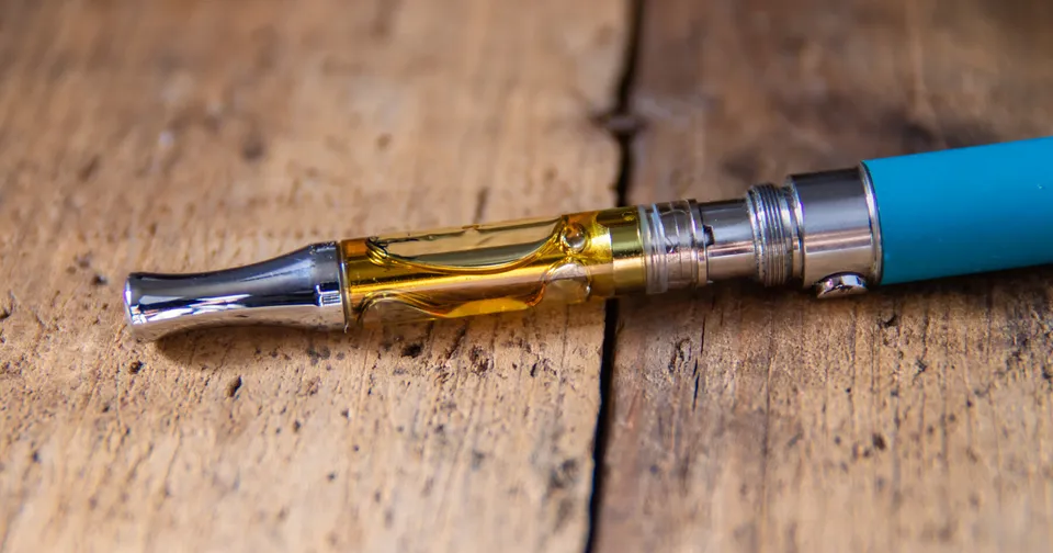 Close-up of a blue electronic cigarette with a silver and amber mouthpiece on a wooden surface