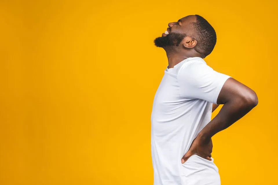 Man in white shirt stretching backward against a bright yellow background